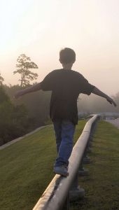 boy balancing on pipeline
